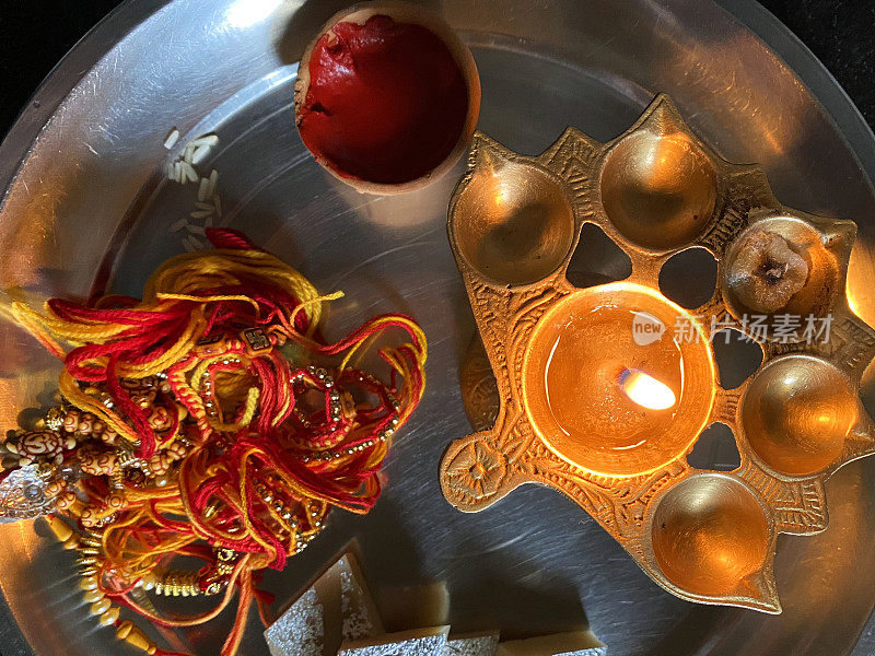 Raksha Bandhan(印度教的友爱节)的rakhi塔利(rakhi thali)，未碎的米粒(Akshat)，一罐sindoor(红色化妆粉)，rakhi(串手镯)，Kaju kati(腰果糖糖果)，点燃的Diya(油灯)，升高的视野